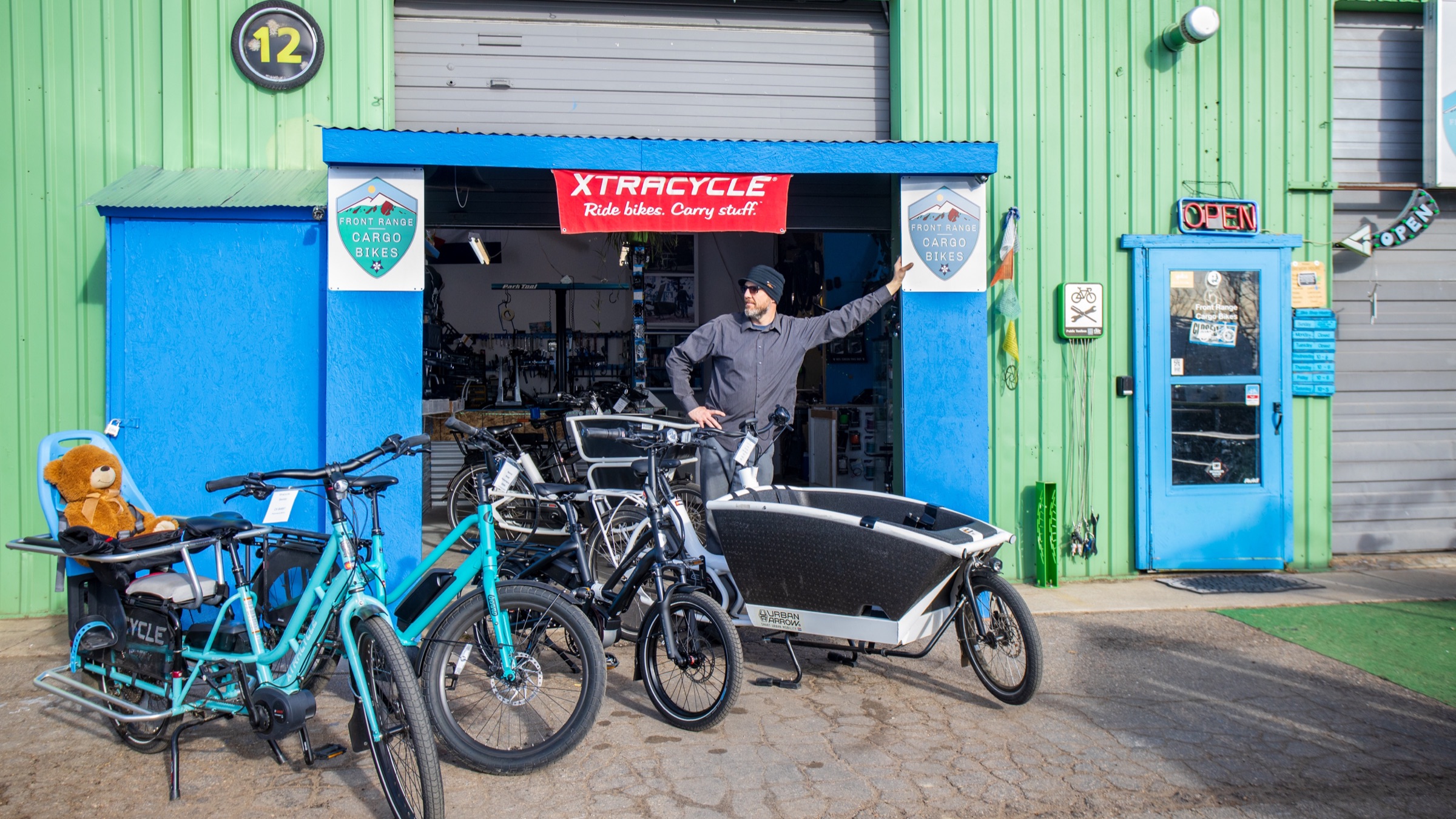 Ryan standing with cargo bikes outside the Front Range Cargo Bikes shop in Boulder