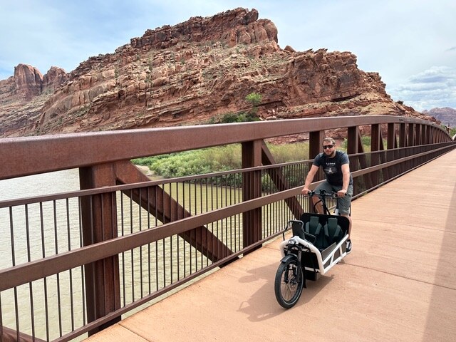 Ryan riding a family cargo bike on a bridge