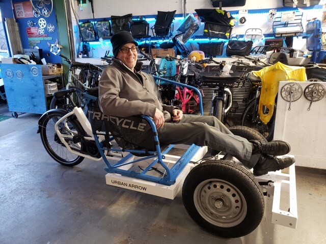 Ryan seated on a cargo bike inside the shop