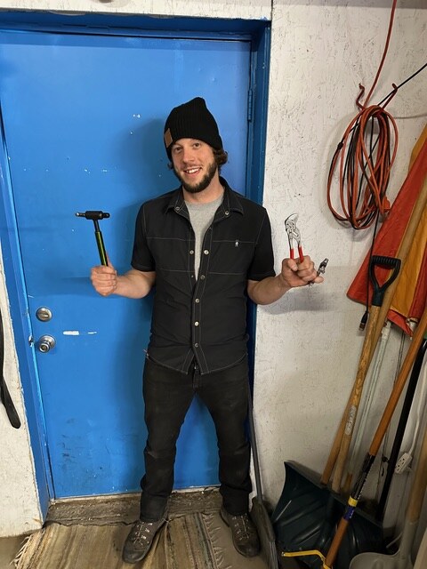 Zach holding bike tools inside the shop